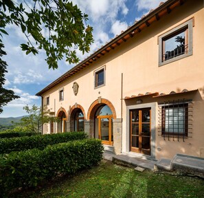 Un edificio a due piani con facciata beige, finestre ad arco e tetto in tegole.