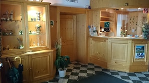 A wooden interior with a checkered floor, a reception desk, and glass display cabinets with various items. - Gasthof Grabenwirt (Irdning-Donnersbachtal)