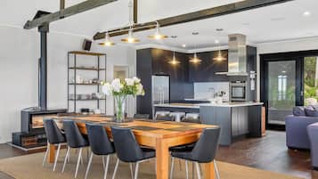A modern kitchen with dark cabinetry, a central island, and a dining area with a wooden table and black chairs.