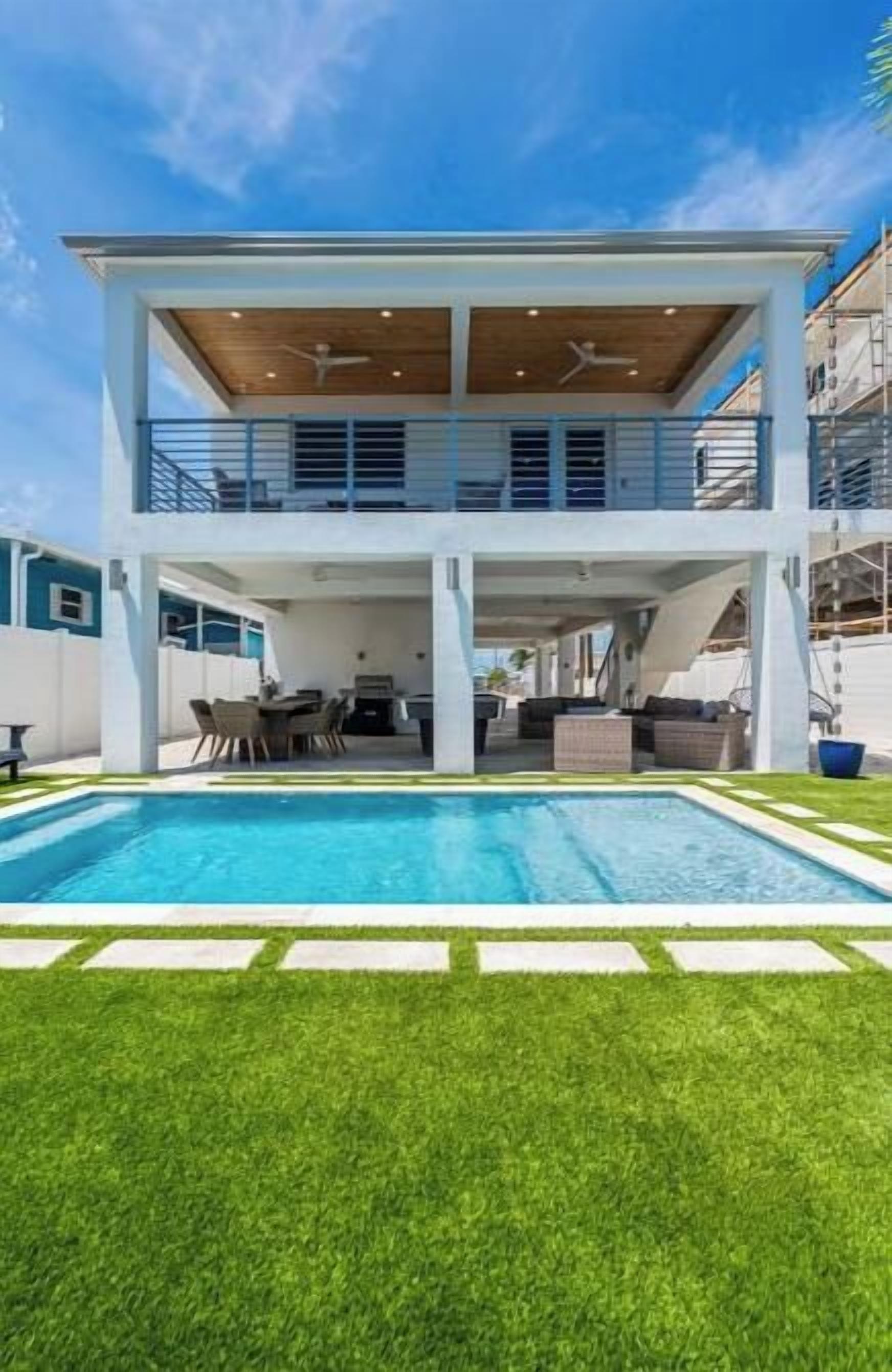 A two-story house with a swimming pool, outdoor seating, and a covered patio.