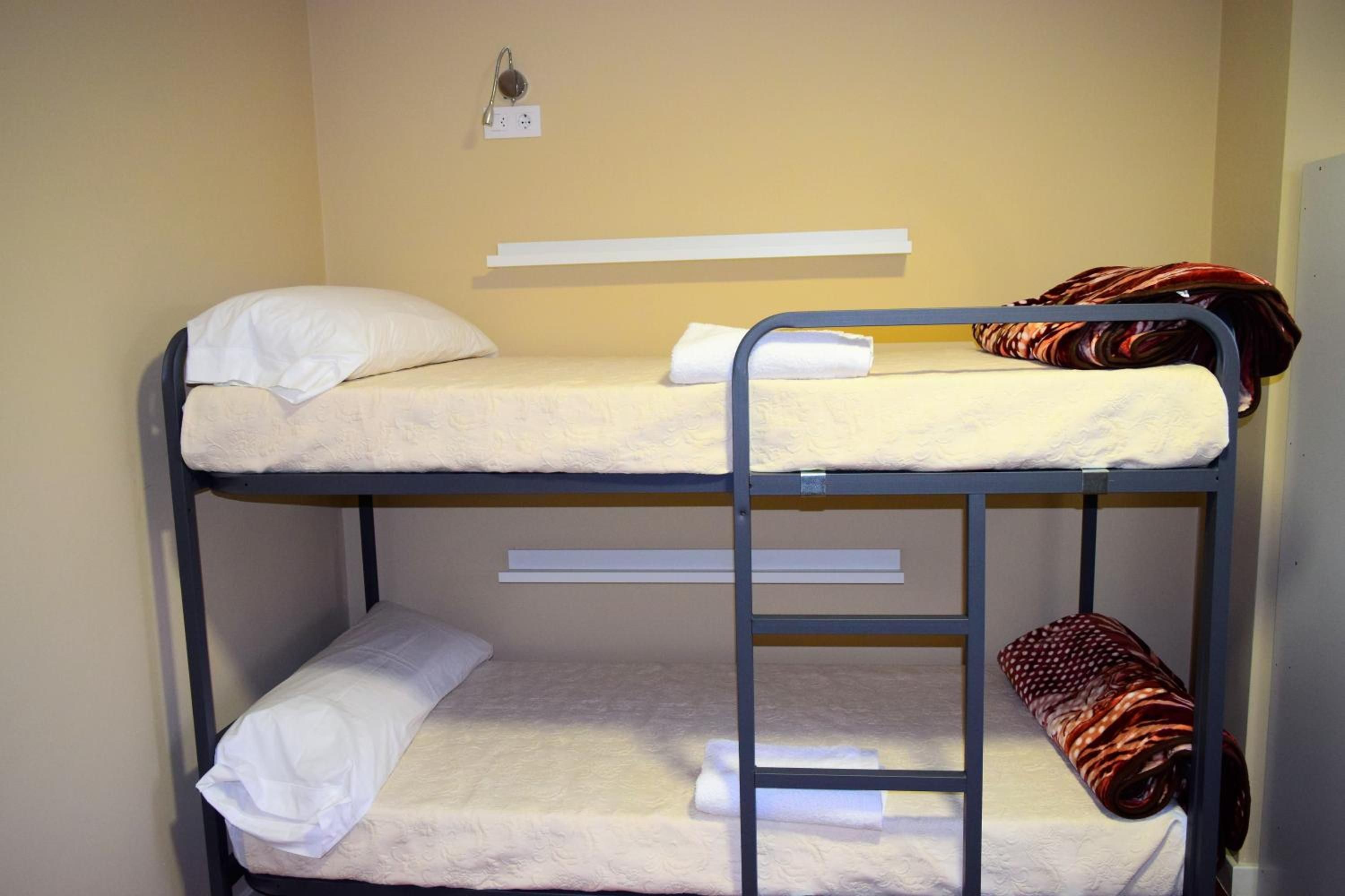 A bunk bed room with a white mattress, a pillow, and a striped blanket.