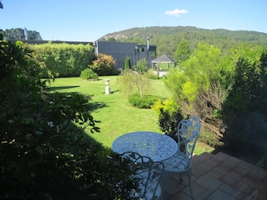 A garden with a patio table and chairs, a white birdbath, and a gazebo. - Golfview Lodge (Bowral)