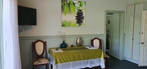 A dining area with a table set for two, a painting above, and a closed door to the right. - Golfview Lodge (Bowral)
