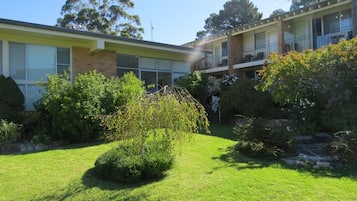 A two-story building with a flat roof, large windows, and a balcony on the upper floor.
