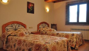 Un dormitorio con dos camas, una ventana con persianas y un radiador.