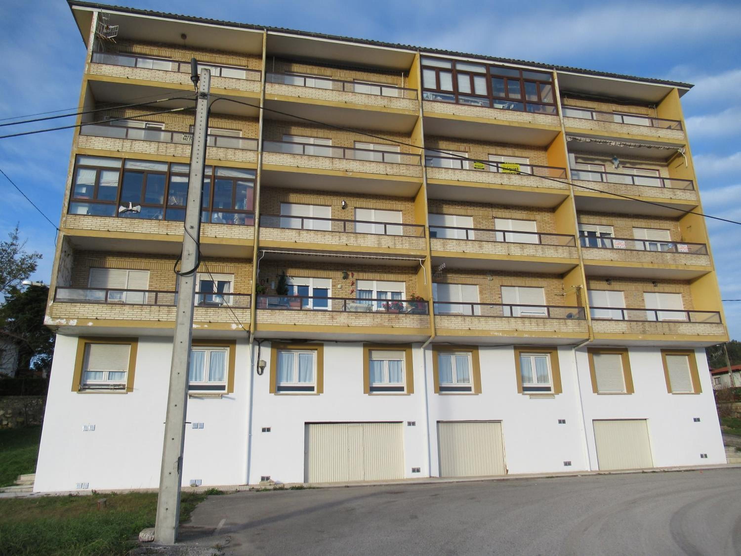 Un edificio de varios pisos con balcones, ventanas y un portón de garaje.