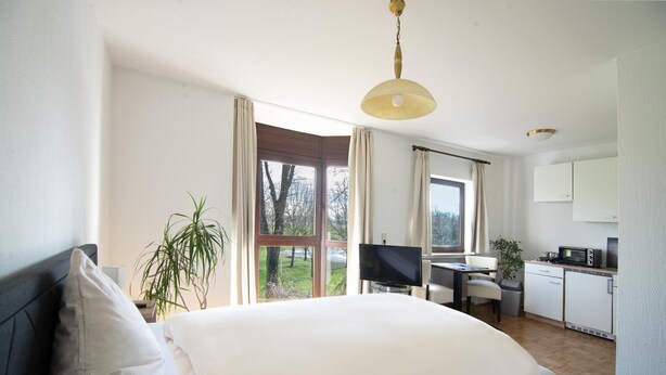 Ein modernes Schlafzimmer mit einem großen Bett, einem Schreibtisch und einer Küchenzeile.