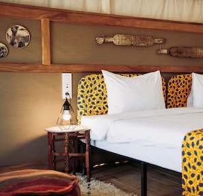 A bedroom with a bed, a nightstand with a lamp, and a wall-mounted power outlet.