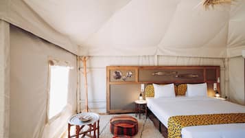 A tented room with a bed, a small table, and a lamp.