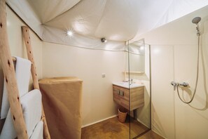 A bathroom with a wooden ladder, a sink with a mirror, and a shower.