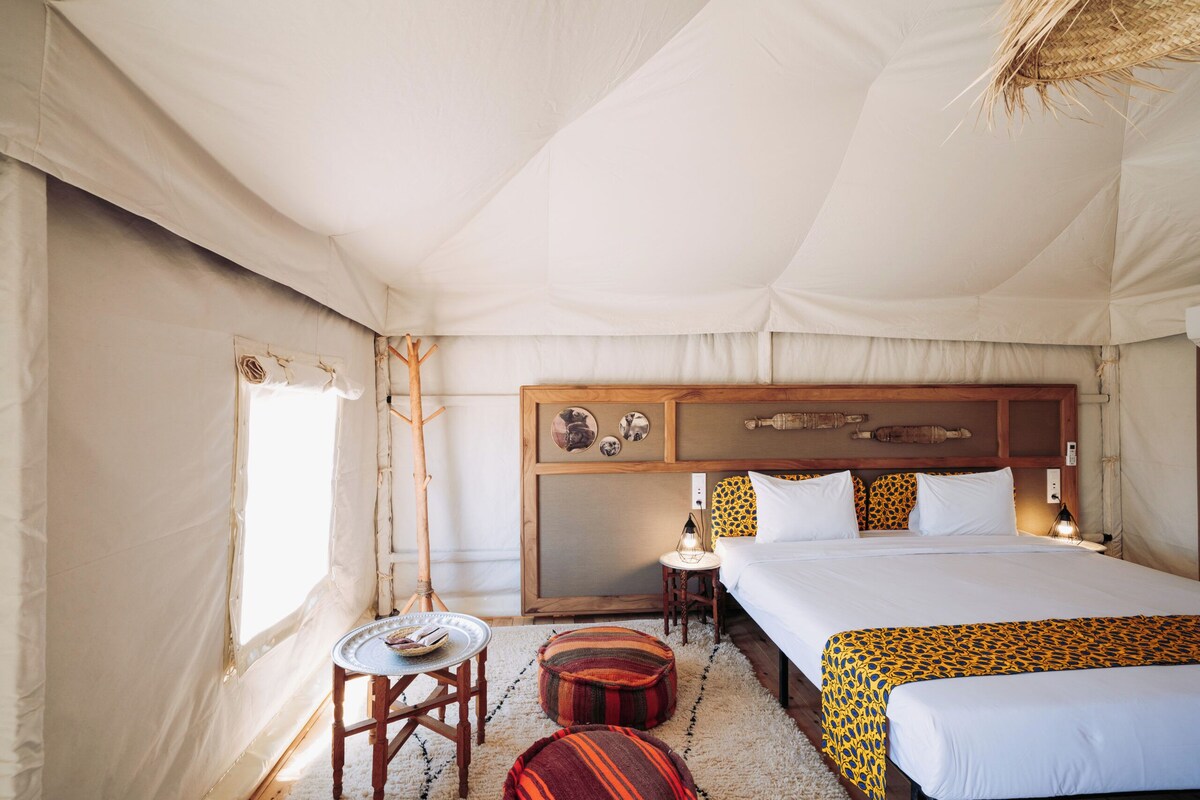 Una habitación con carpa, una cama, una mesita y una lámpara.