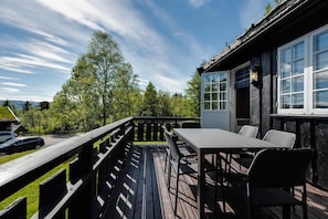 Terraza exterior con mesa y sillas, con vistas a una zona boscosa.