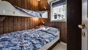 A bedroom with a bunk bed, wooden walls, a window with a view, and a door with a handle. - Bitigrenda N (Øystre Slidre)