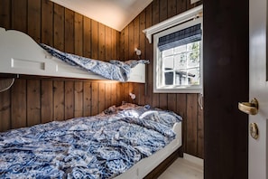 Un dormitorio con literas, paredes de madera, un ventanal y una puerta con manija.
