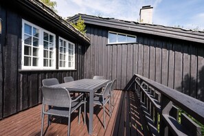 Eine Terrasse mit Tisch und Stühlen, Holzbalkonen und einem Gebäude mit Fenstern.