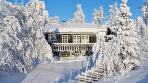 Una casa de madera rodeada de árboles cubiertos de nieve.