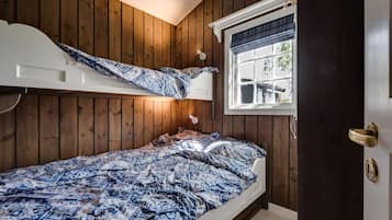 Een slaapkamer met een stapelbed, houten wanden, een raam met uitzicht en een deur met een handgreep.