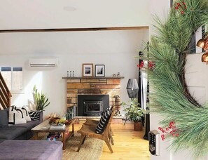 Un salon chaleureux avec une cheminée, un canapé, une table basse et un fauteuil.