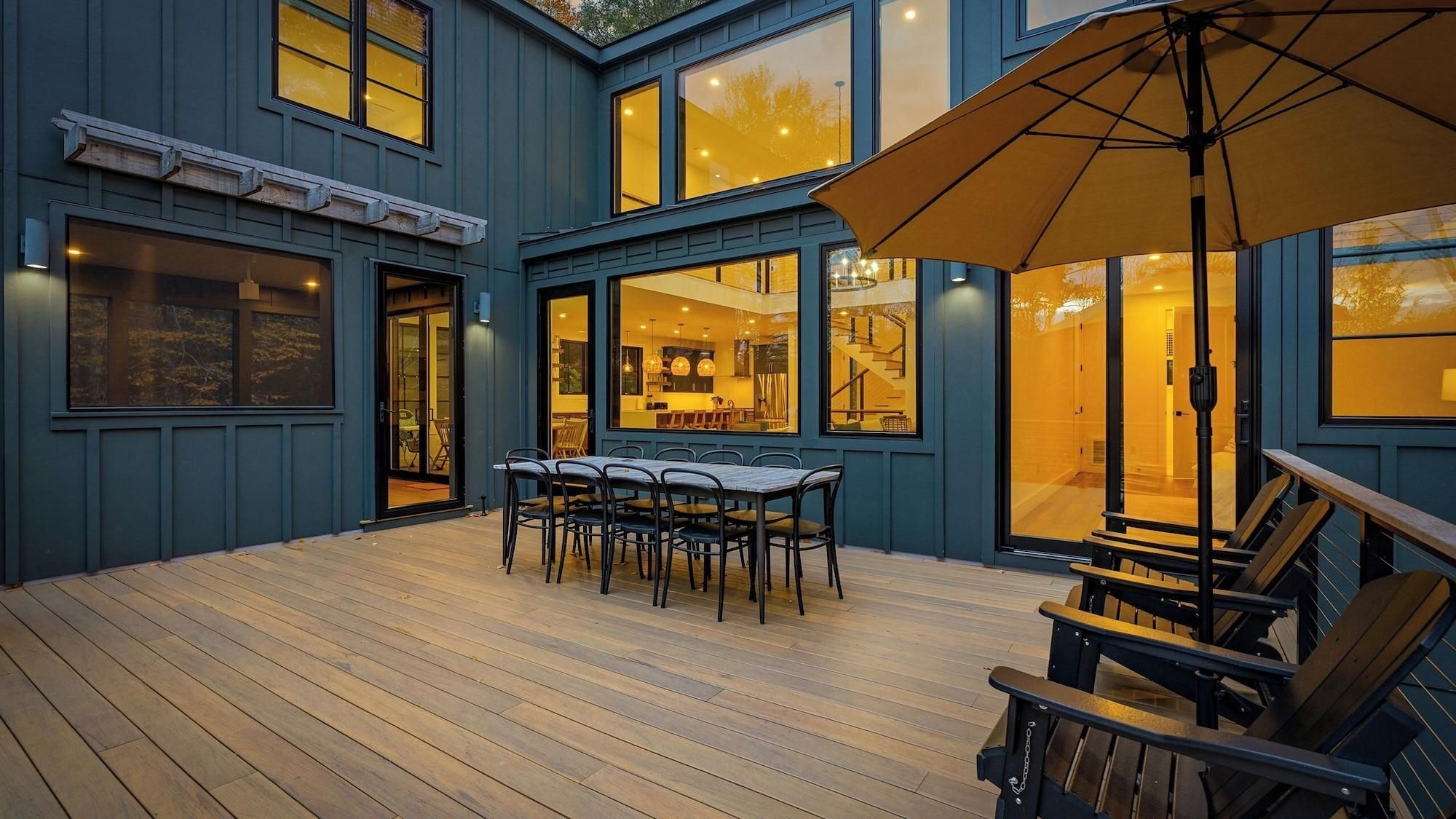 A wooden deck with a table and chairs, a bench, and a large umbrella.