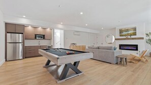 A modern living room with a pool table, a sofa, a TV, and a fireplace. - Forget-me-not By Avantstay Bold Lakefront Escape (Monterey)