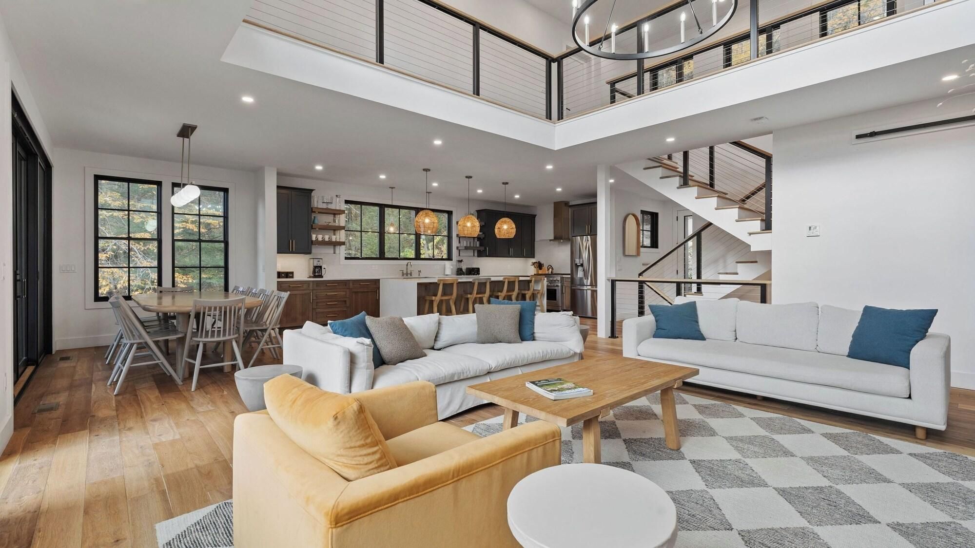 A spacious living area with a high ceiling, a dining area with a view, and a kitchen with modern appliances.