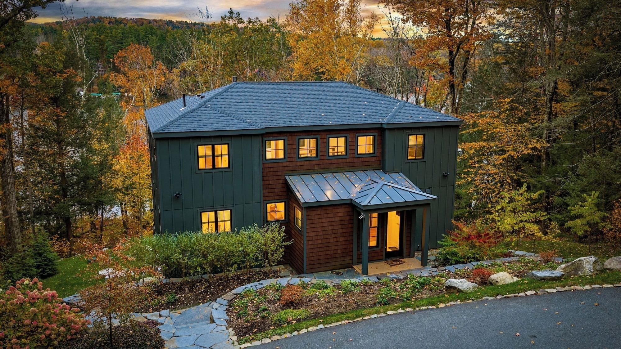 A two-story house with a dark exterior, multiple windows, and a sloped roof.