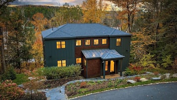 A two-story house with a dark exterior, multiple windows, and a sloped roof.