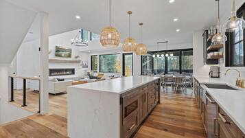 A modern kitchen with a large island, wooden cabinets, and pendant lighting.