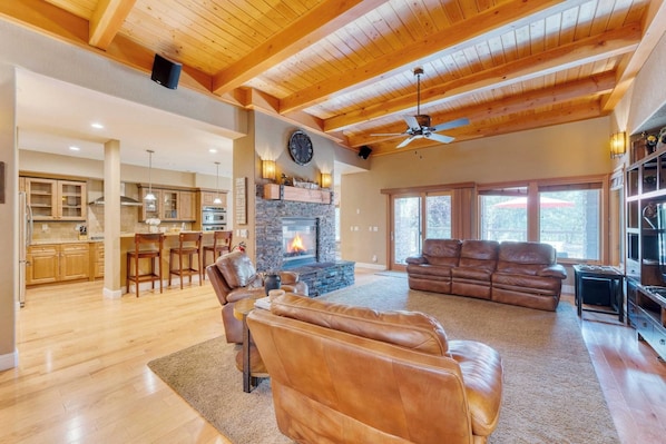 A spacious living area with a fireplace, leather sofas, and a dining area with wooden cabinets. - Luxe All-season Retreat By Avantstay Prime Locat (Truckee)