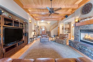 A spacious living room with a fireplace, leather sofas, a television, and a ceiling fan. - Luxe All-season Retreat By Avantstay Prime Locat (Truckee)