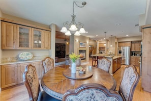A spacious kitchen with wooden cabinets, a central island, and a dining area with a round table and chairs. - Luxe All-season Retreat By Avantstay Prime Locat (Truckee)