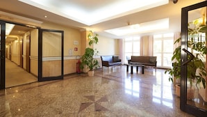 A hotel lobby with a marble floor, a reception desk, a sofa, and a large window. - Solidaris (Kedzierzyn Kozle)