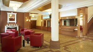 A lobby with red seating, a reception desk, and a staircase. - Solidaris (Kedzierzyn Kozle)