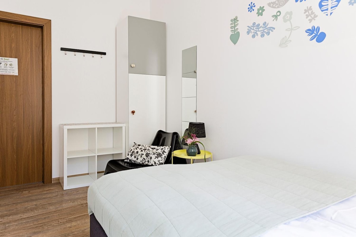 A bedroom with a bed, a desk, a chair, a wardrobe, and a mirror.