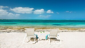 Two beach chairs facing a clear blue sea with a sandy beach in the foreground. - Callaloo Cottage (Providenciales)