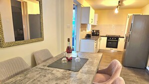 Un coin repas avec une table en marbre, deux verres à vin et une bouteille de vin.