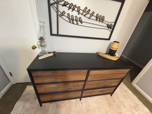 Une commode en bois noir avec des tiroirs, un vase en verre et une petite figurine posée sur le dessus.