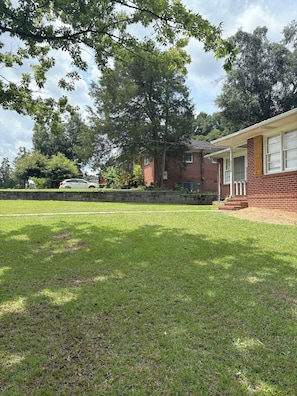 A residential property with a brick house, a front porch, and a lawn.