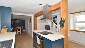 A compact kitchen with a central island, wooden accents, and a view to the outside. - 2bed Cottage Johnshaven - Family Friendy (Montrose)