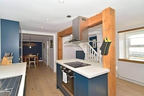 A compact kitchen with a central island, wooden accents, and a view to the outside. - 2bed Cottage Johnshaven - Family Friendy (Montrose)