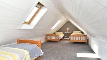 A small attic bedroom with two wooden beds, a skylight, and a radiator.