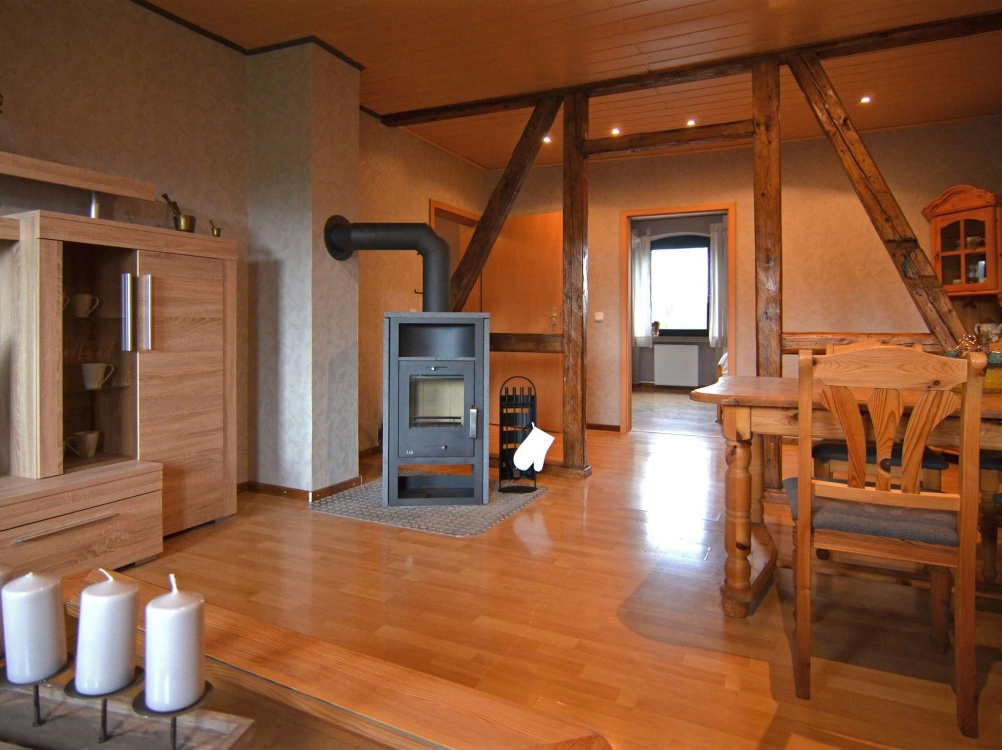 A cozy room with a wood-burning stove, wooden furniture, and a dining table.