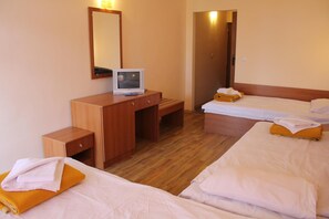 A hotel room with a wooden desk, a television, two beds with white linens and orange pillows, and a mirror on the wall. - Complex Dobrudja (Balchik)
