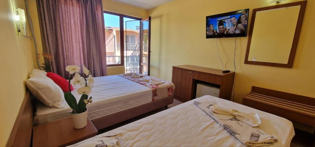 Una habitación de hotel con dos camas, televisión, escritorio y ventana con cortinas.