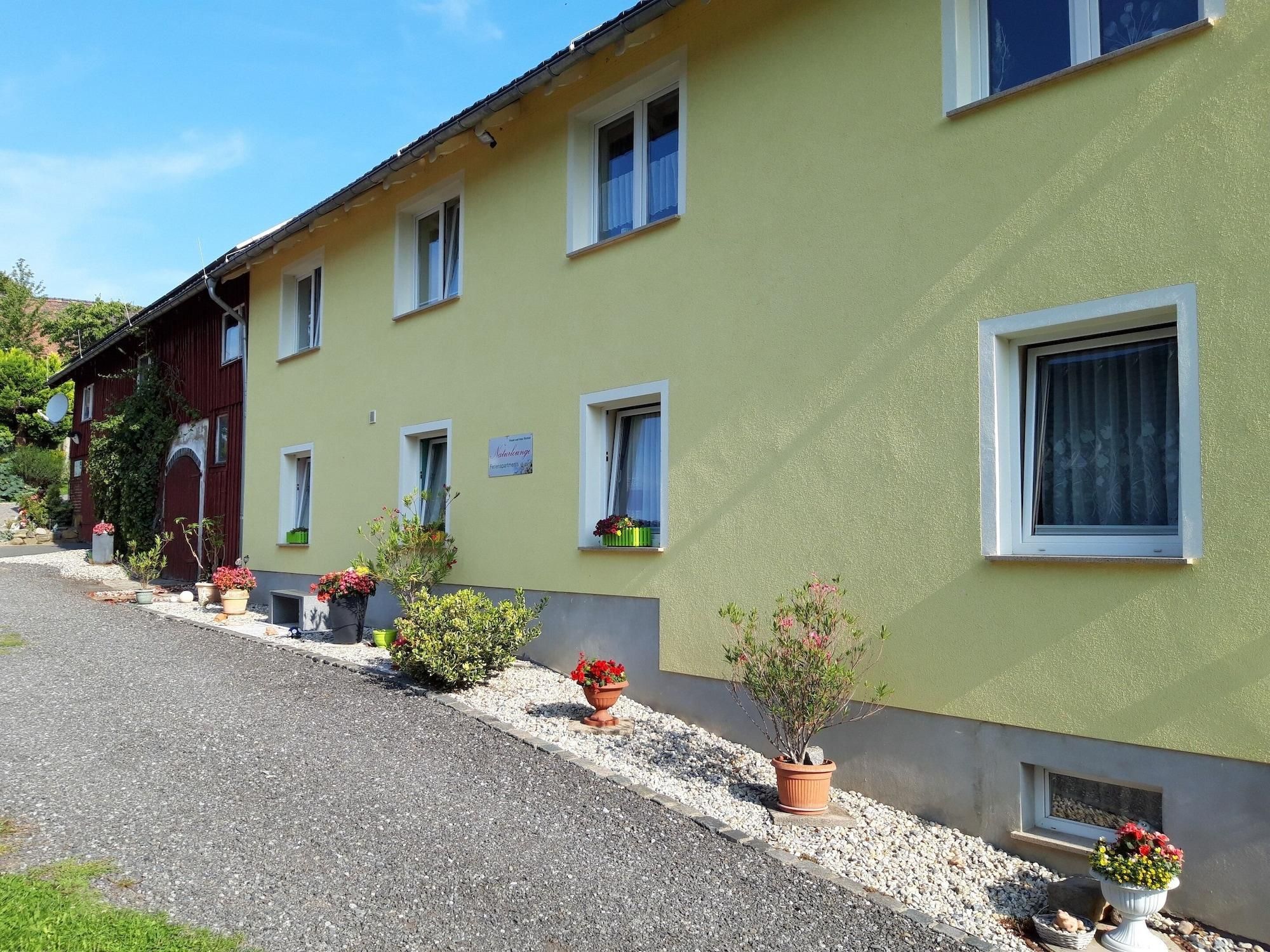 A row of two-story buildings with multiple windows, some with curtains, and a gravel driveway.