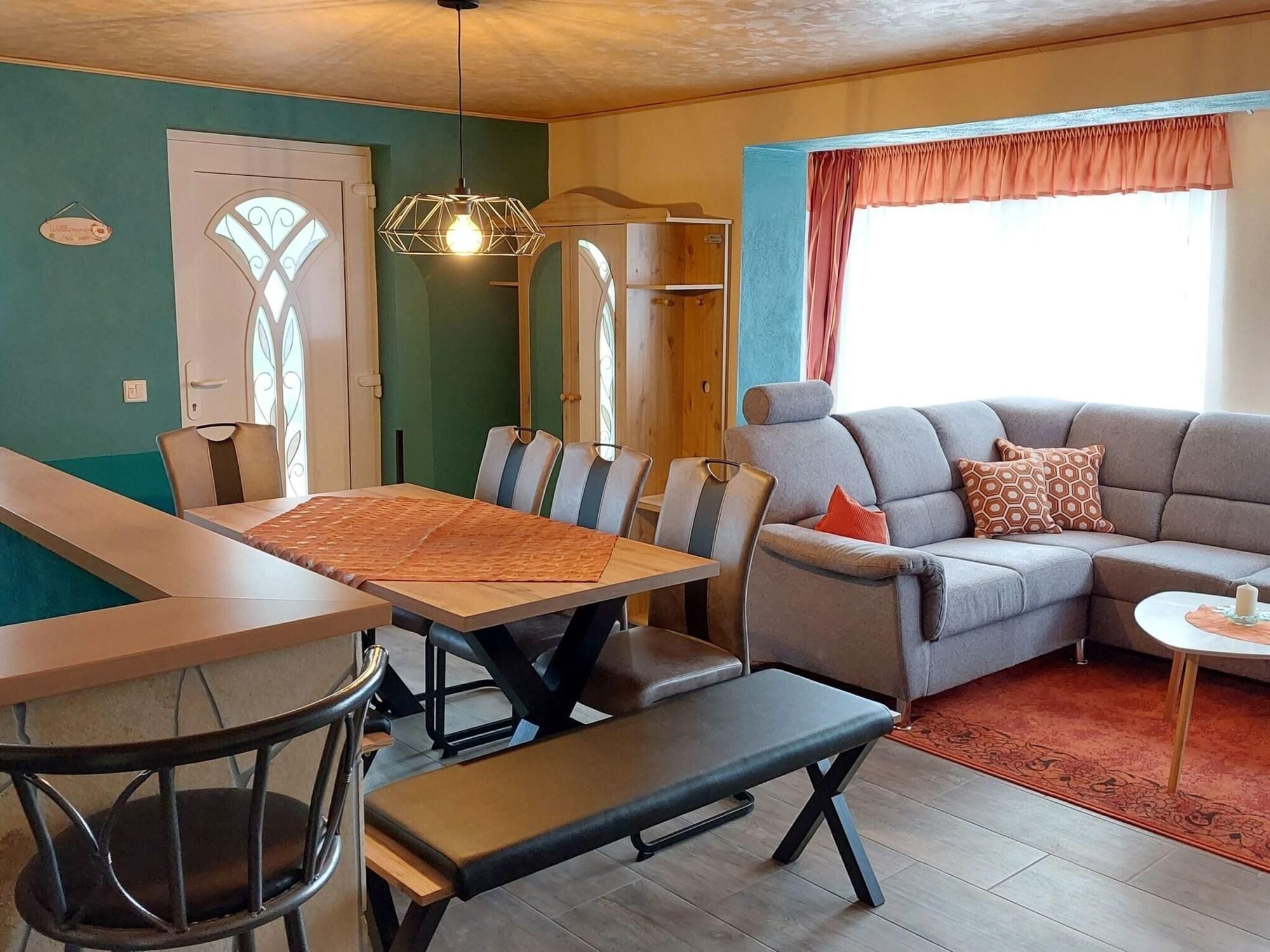 Een zithoek met een tafel en stoelen, een bank en een raam met gordijnen.