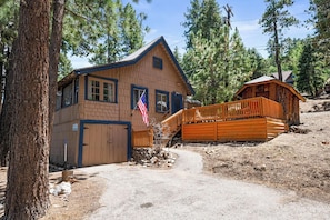 A wooden cabin with a garage, a porch, and an American flag. - All Seasons Chateau (Big Bear Lake)