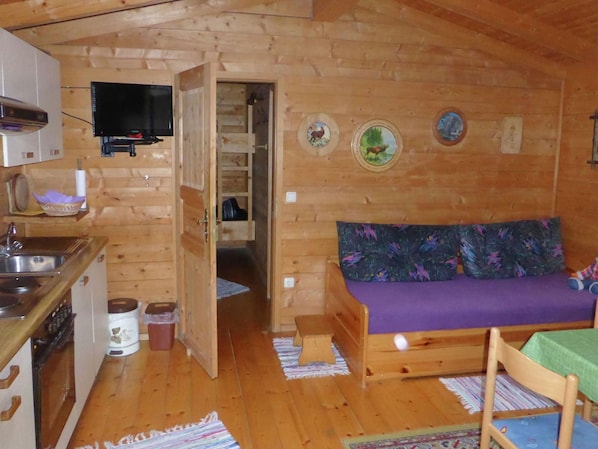 Uma cabana aconchegante com cozinha compacta, um sofá e uma pequena mesa de jantar.