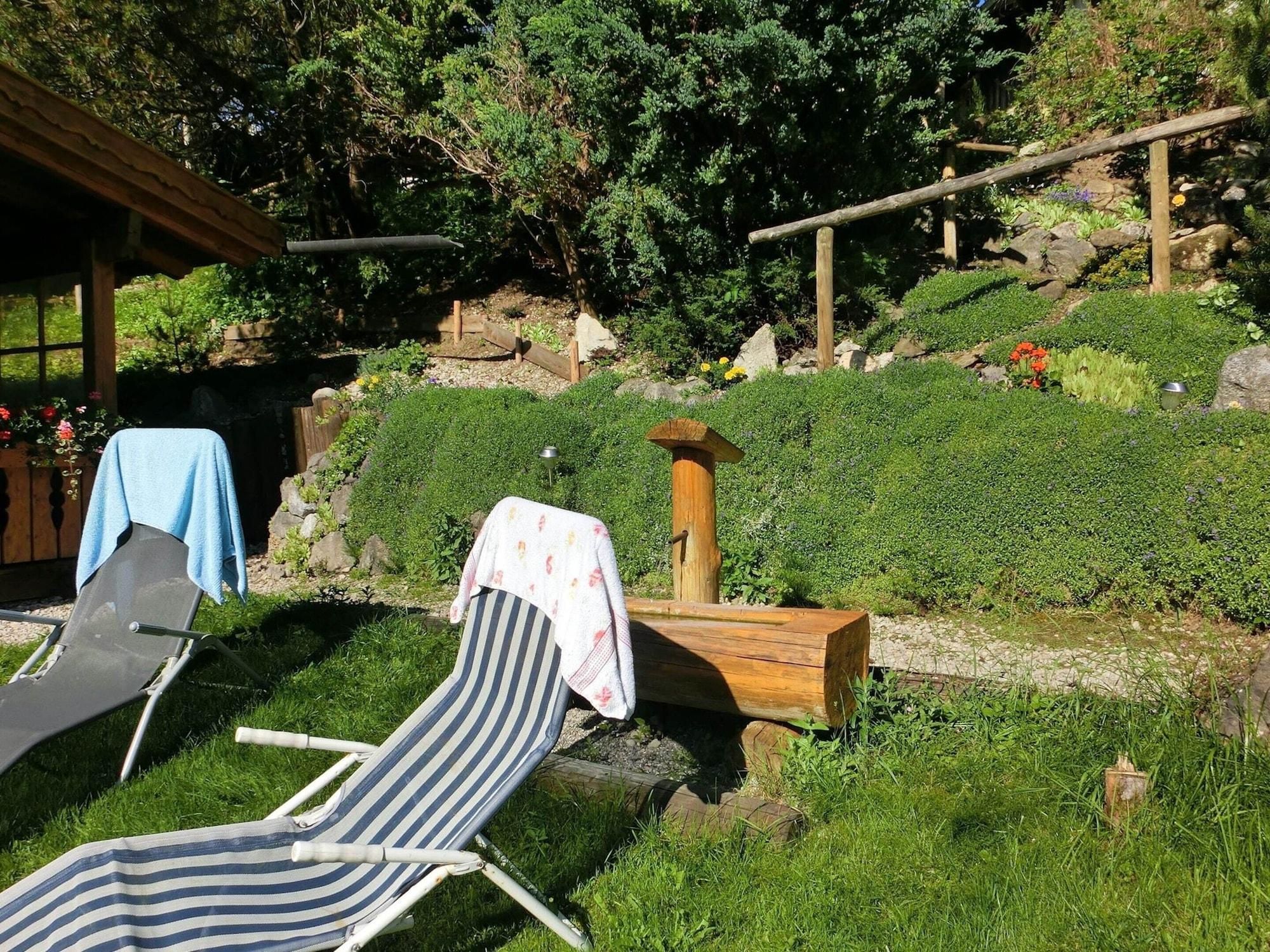 A garden with a wooden structure, a wooden post, and a chair with a towel.