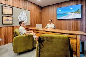 Una habitación con un panel de madera, un reloj grande y un televisor que muestra una escena de playa.